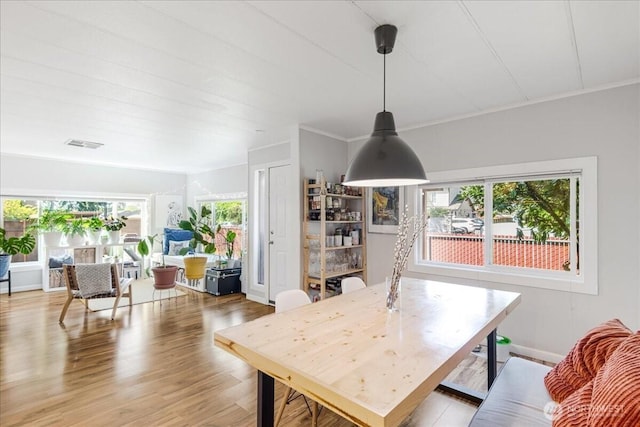 dining space featuring light wood-type flooring, crown molding, and visible vents