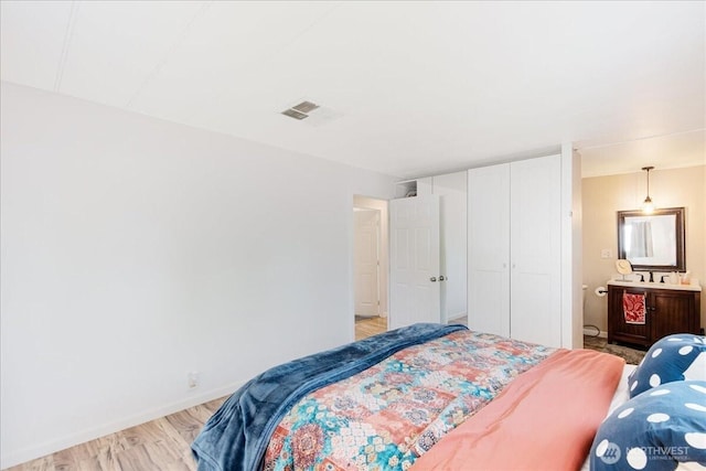 bedroom with visible vents, baseboards, a closet, light wood-style floors, and ensuite bathroom