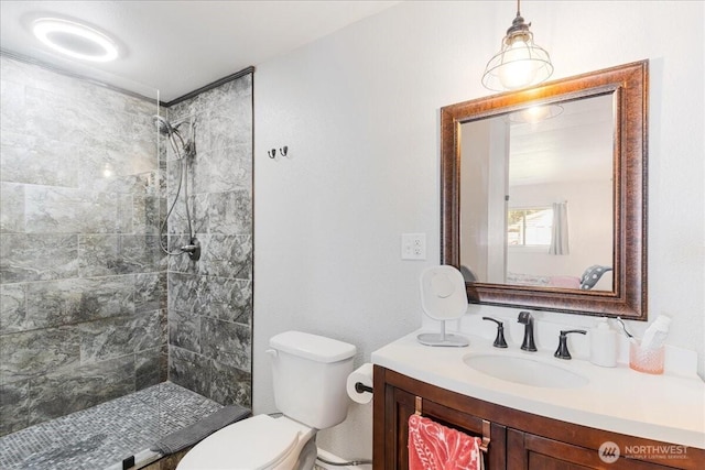 bathroom featuring vanity, a tile shower, and toilet