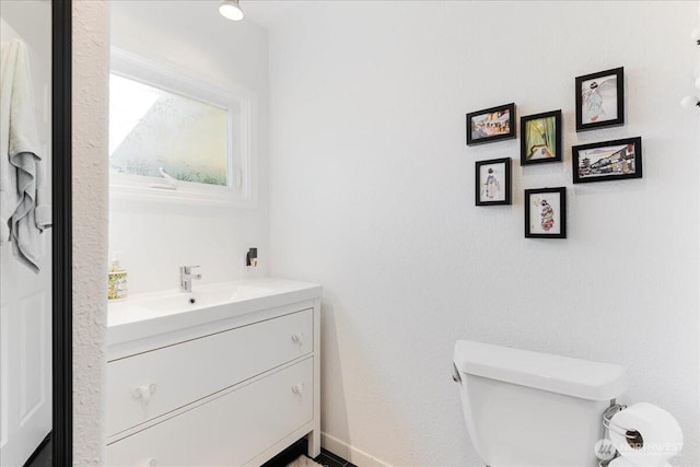 half bath with vanity, baseboards, and toilet