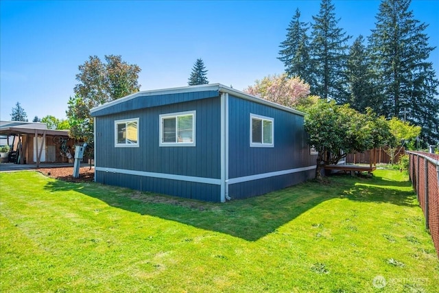 view of side of home featuring a lawn and fence