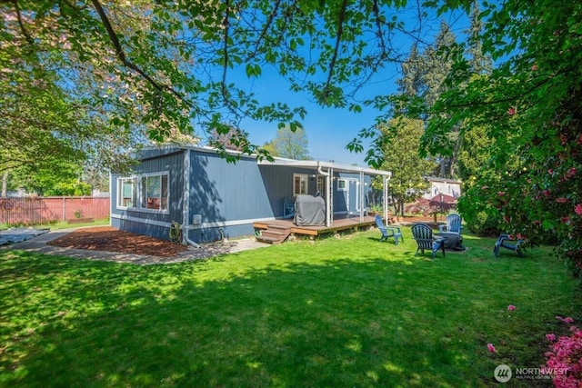 rear view of property featuring fence, a yard, and a deck