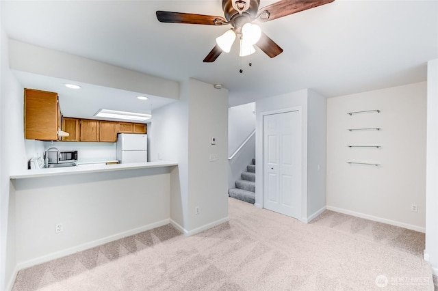 unfurnished living room featuring stairs, light carpet, baseboards, ceiling fan, and recessed lighting