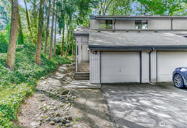 exterior space with aphalt driveway, a shingled roof, and a garage
