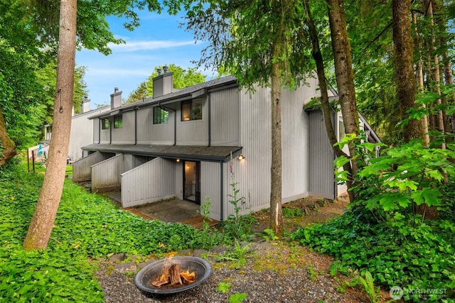 11547 SE 175th St Unit 1, Renton, WA 98058 - back of property featuring an outdoor fire pit, a chimney, and a shingled roof