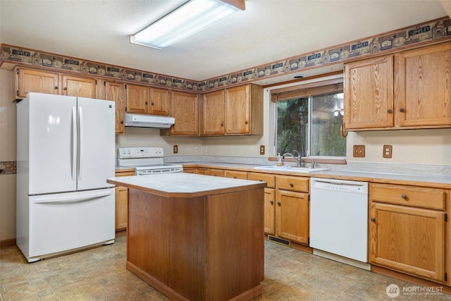 kitchen featuring a kitchen island, white appliances, light countertops, under cabinet range hood, and a sink