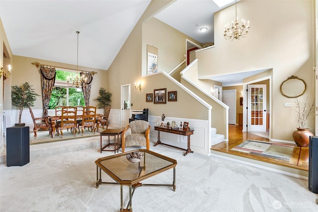 living room featuring carpet floors, stairs, a notable chandelier, and high vaulted ceiling