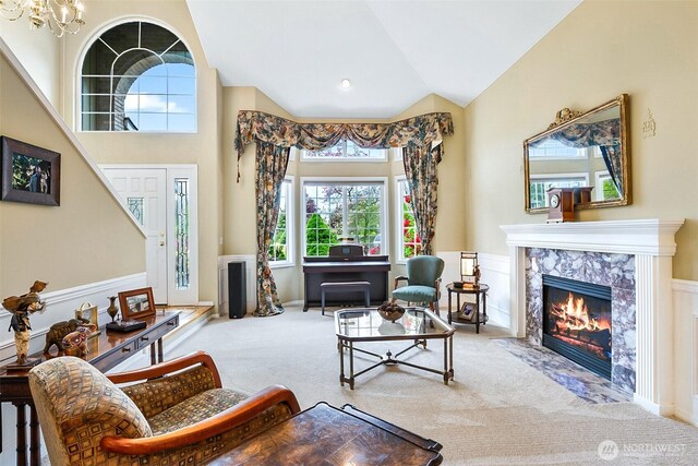 carpeted living area with a wainscoted wall, a fireplace, a chandelier, and a wealth of natural light