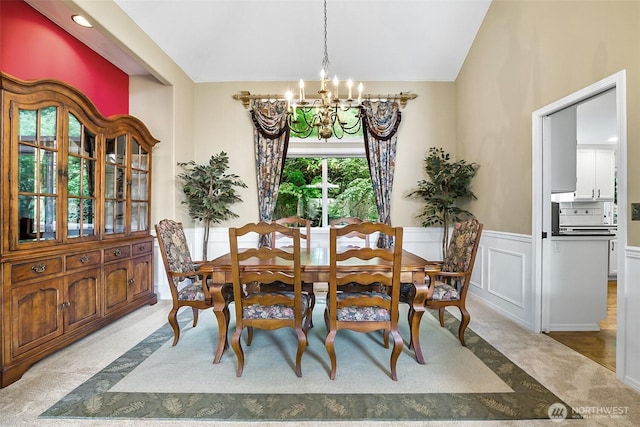 dining room with vaulted ceiling, a wainscoted wall, carpet flooring, and a chandelier