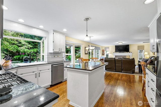 kitchen featuring a kitchen island, hanging light fixtures, dishwasher, a sink, and white cabinets