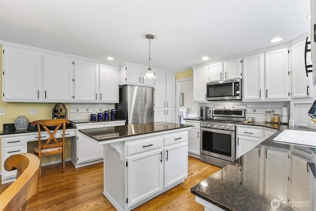 kitchen featuring a kitchen island, backsplash, white cabinets, and appliances with stainless steel finishes