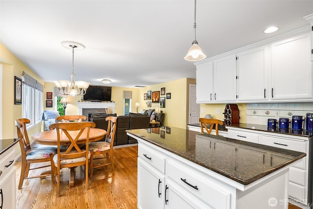 kitchen with white cabinetry, decorative light fixtures, a chandelier, and light wood-type flooring