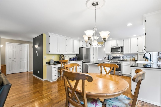 dining space with recessed lighting, baseboards, a chandelier, and wood finished floors