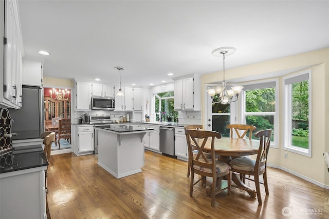 kitchen featuring an inviting chandelier, white cabinetry, backsplash, and stainless steel appliances