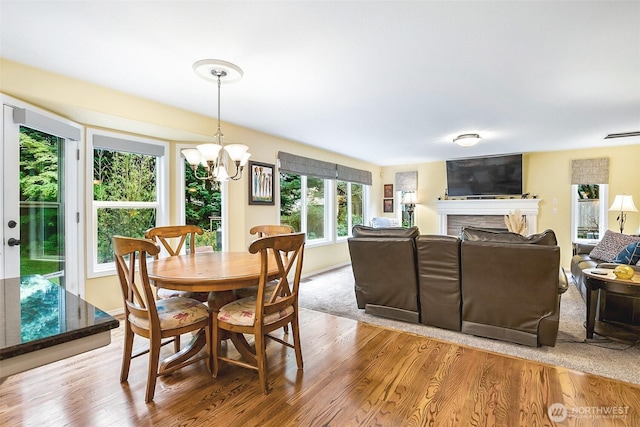dining area with an inviting chandelier, baseboards, a fireplace, and wood finished floors