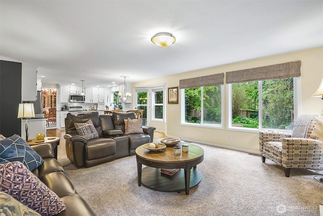 living room featuring baseboards, a notable chandelier, and light carpet