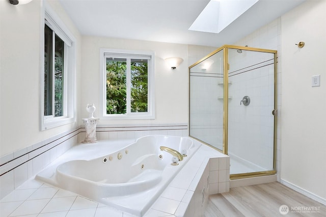 bathroom featuring a whirlpool tub, wood finished floors, a skylight, and a shower stall