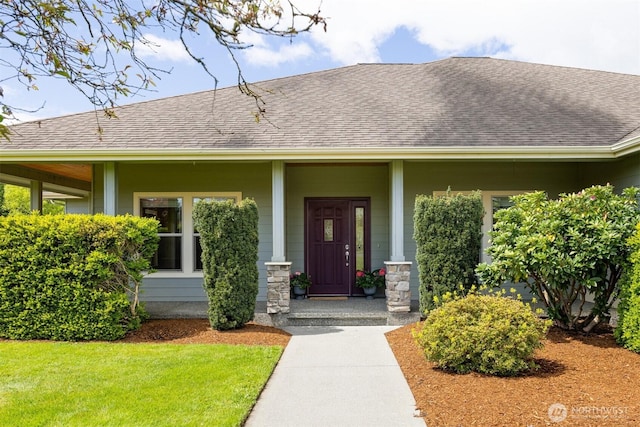 doorway to property featuring a porch and a shingled roof