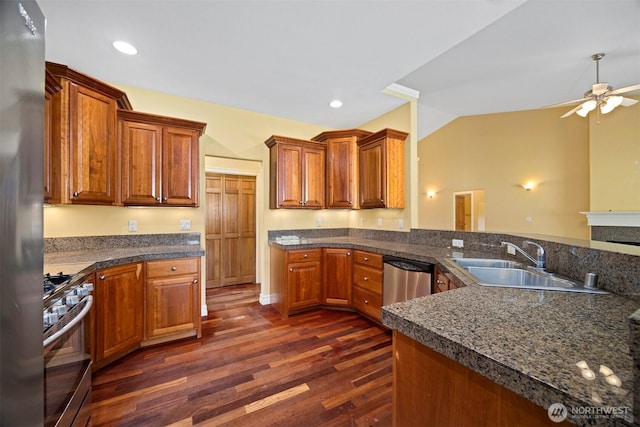 kitchen featuring dark wood-style flooring, a sink, brown cabinetry, stainless steel appliances, and a ceiling fan