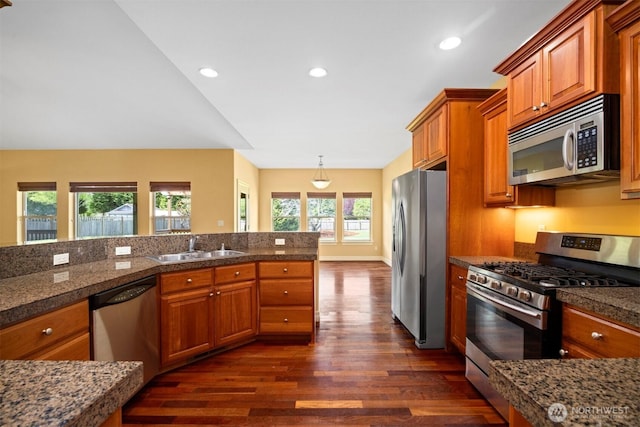 kitchen featuring appliances with stainless steel finishes, a sink, brown cabinetry, tile countertops, and dark wood-style floors