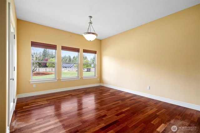 unfurnished room with baseboards and dark wood-style floors