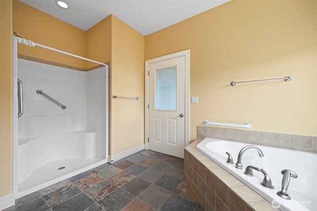 full bathroom with baseboards, walk in shower, a bath, and stone finish floor