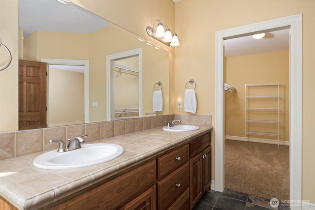 full bath with a sink, double vanity, and a spacious closet
