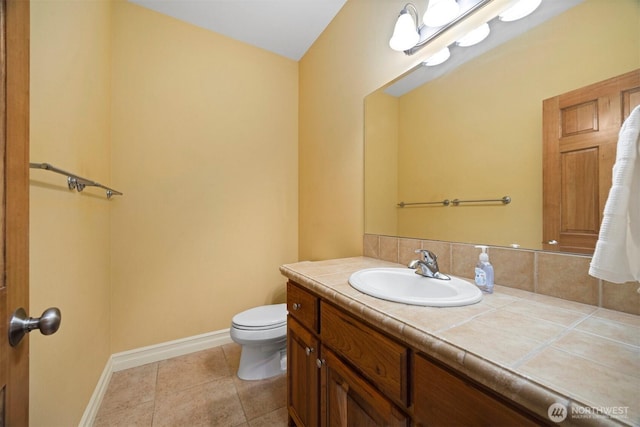 half bath with tasteful backsplash, tile patterned flooring, vanity, baseboards, and toilet