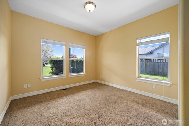 unfurnished room with visible vents, a healthy amount of sunlight, and carpet