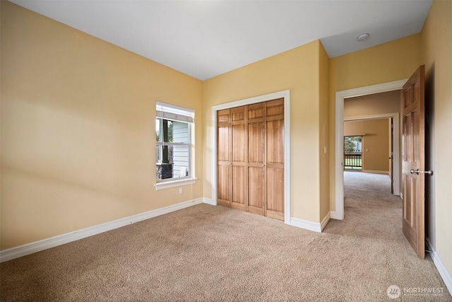 unfurnished bedroom featuring carpet floors, multiple windows, and baseboards