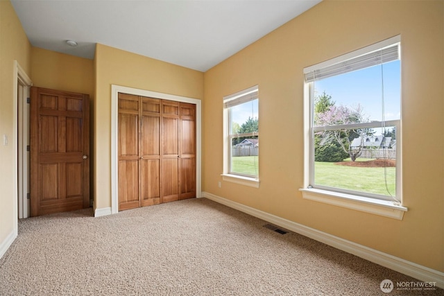 unfurnished bedroom featuring visible vents, baseboards, multiple windows, and a closet
