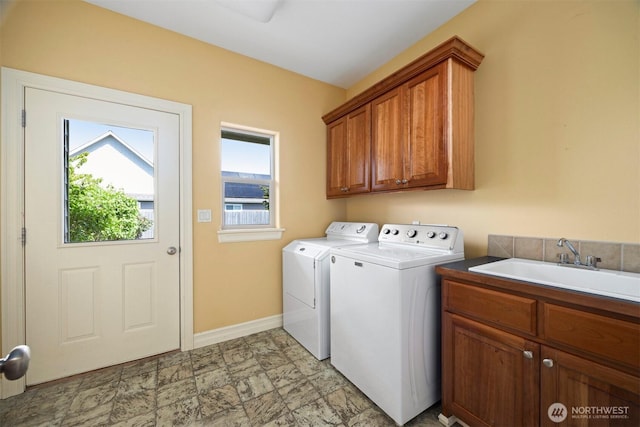 laundry room with baseboards, a sink, cabinet space, and independent washer and dryer