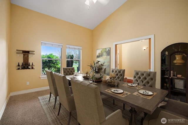 dining space featuring high vaulted ceiling, baseboards, a ceiling fan, and carpet flooring
