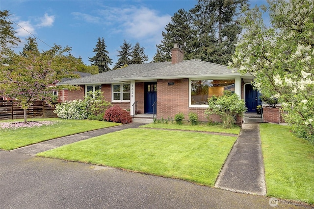 view of front of property featuring brick siding, a front lawn, roof with shingles, and a chimney