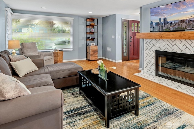 living area featuring baseboards, recessed lighting, a glass covered fireplace, and wood finished floors