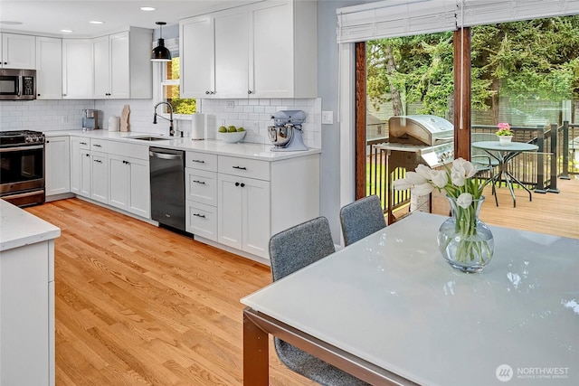 kitchen featuring a sink, stainless steel appliances, white cabinetry, and a healthy amount of sunlight