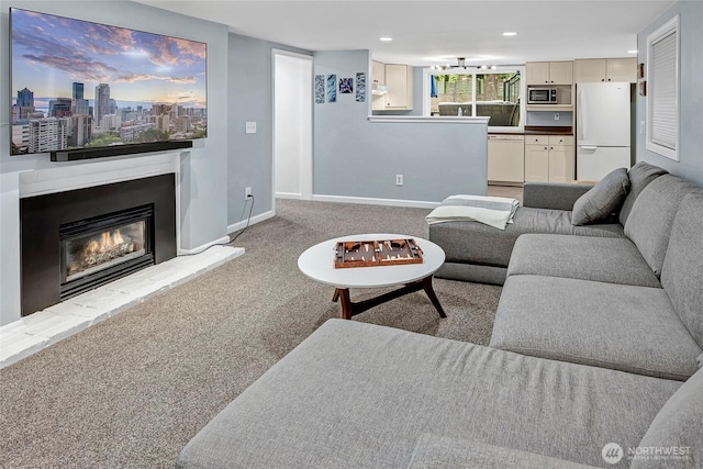 living area with a glass covered fireplace, baseboards, recessed lighting, and carpet floors