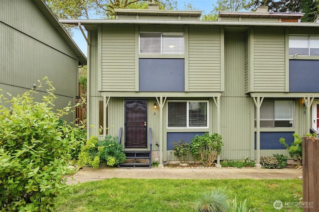 view of front of property with a front yard, a chimney, and entry steps