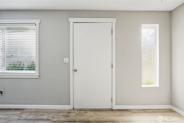 unfurnished bedroom featuring baseboards, wood finished floors, and multiple windows
