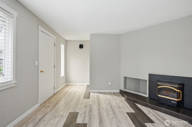 unfurnished living room featuring baseboards, a textured ceiling, and wood finished floors