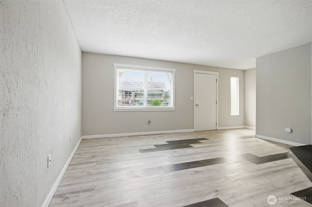 unfurnished living room with a textured ceiling, a wealth of natural light, and light wood-style floors