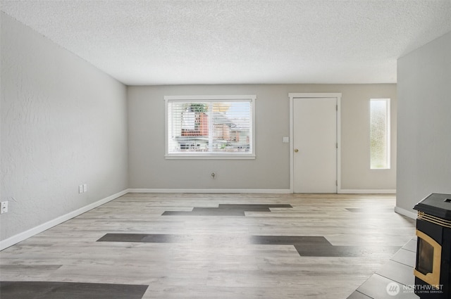 unfurnished living room with baseboards, a textured ceiling, and wood finished floors
