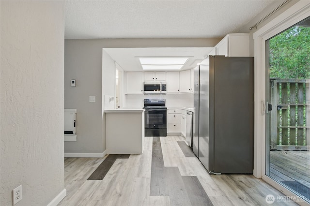 kitchen featuring light wood-style floors, baseboards, light countertops, white cabinets, and stainless steel appliances