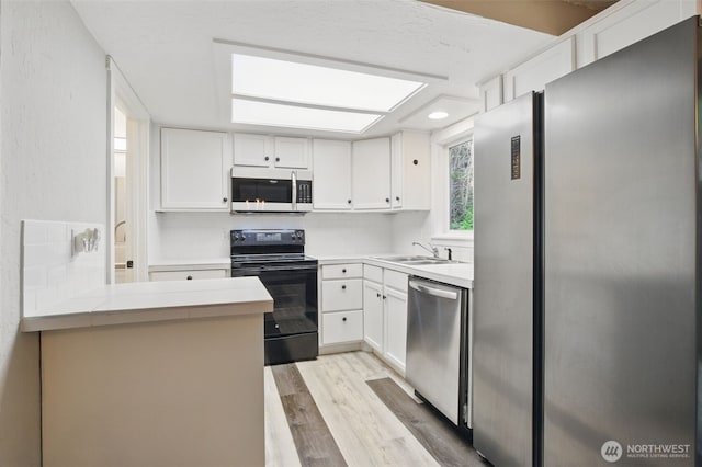 kitchen featuring a sink, appliances with stainless steel finishes, white cabinets, and light wood-style floors