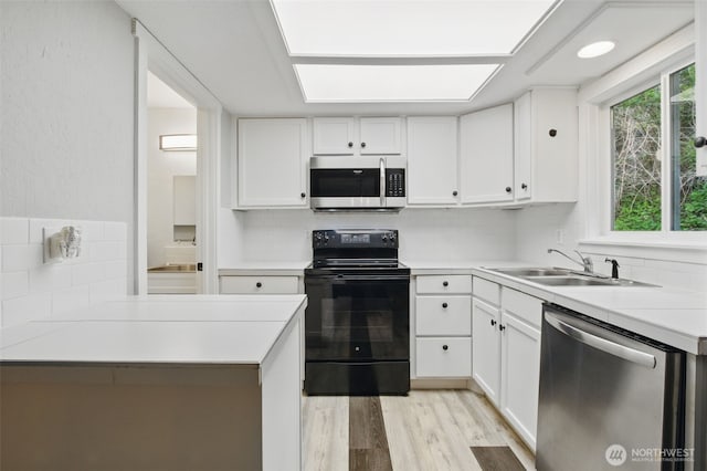 kitchen featuring light wood-style floors, white cabinets, tasteful backsplash, a sink, and stainless steel appliances