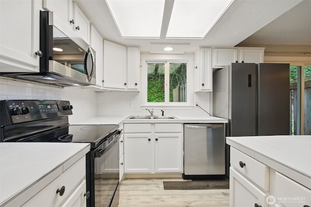 kitchen featuring a sink, light countertops, stainless steel appliances, and white cabinetry