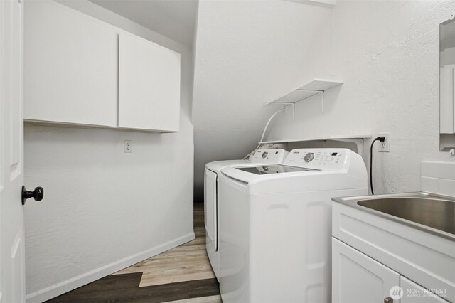 washroom featuring baseboards, cabinet space, light wood-style flooring, and washer and dryer