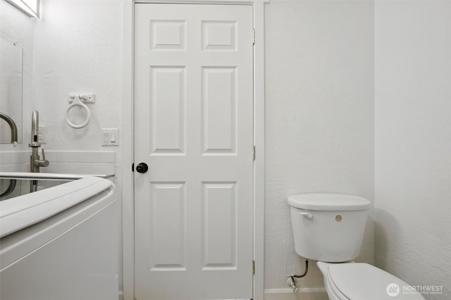 bathroom with a textured wall and toilet