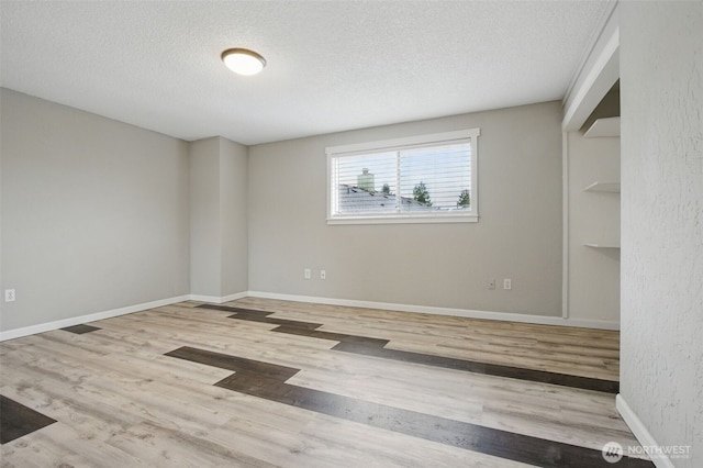 empty room featuring baseboards, a textured ceiling, and wood finished floors