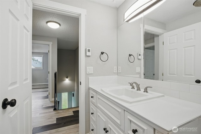 bathroom with vanity, baseboards, a textured ceiling, and wood finished floors